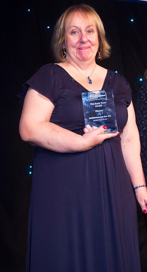Maureen Hunt holding the Early Years Award trophy at an awards evening